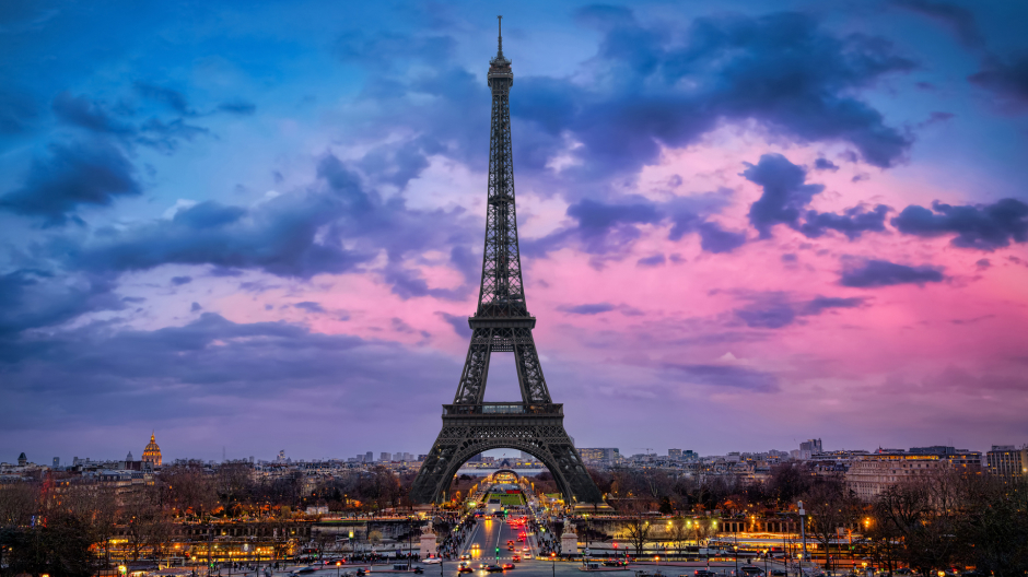 An image of the Eiffel Tower in Paris with a pink and blue sunset sky.